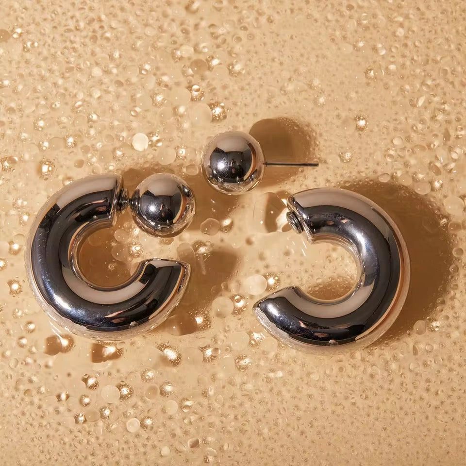 2-in-1 bold midi stainless steel earrings by GRISÉ NYC with detachable ball design and sculptural curved silhouette.