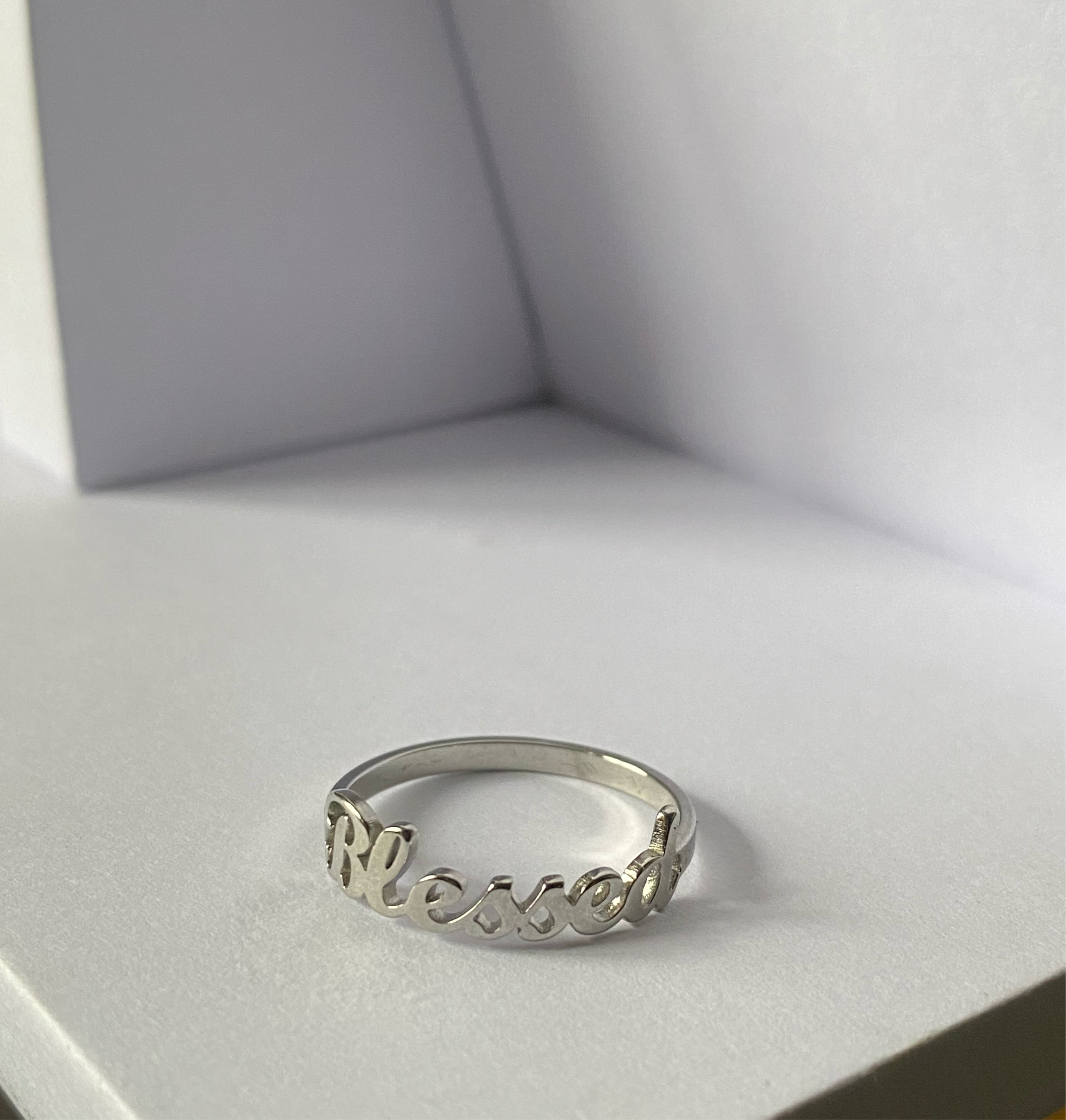 Blessed Ring in polished stainless steel displayed on a minimalist white surface by GRISÉ NYC.