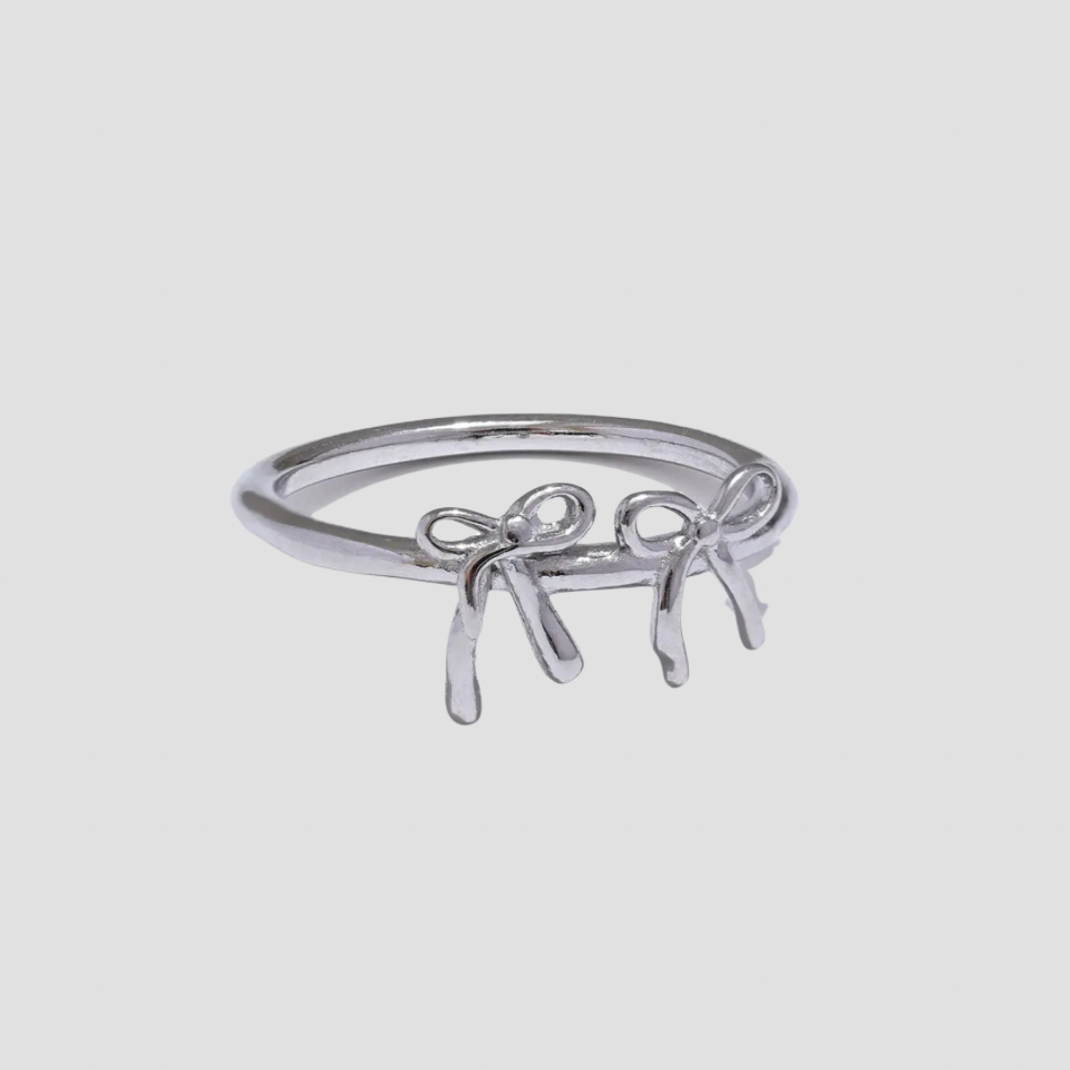Dainty Double Croquette Bow Ring in polished stainless steel featuring two delicate bow designs on a minimalist silver band by GRISÉ NYC.