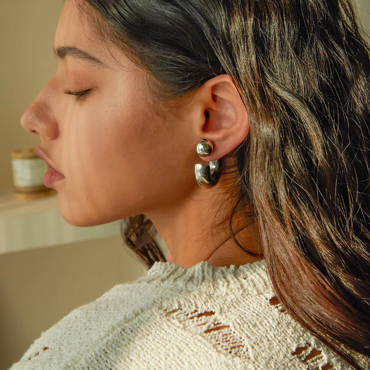 2-in-1 bold midi stainless steel earrings by GRISÉ NYC with detachable ball design and sculptural curved silhouette on model.