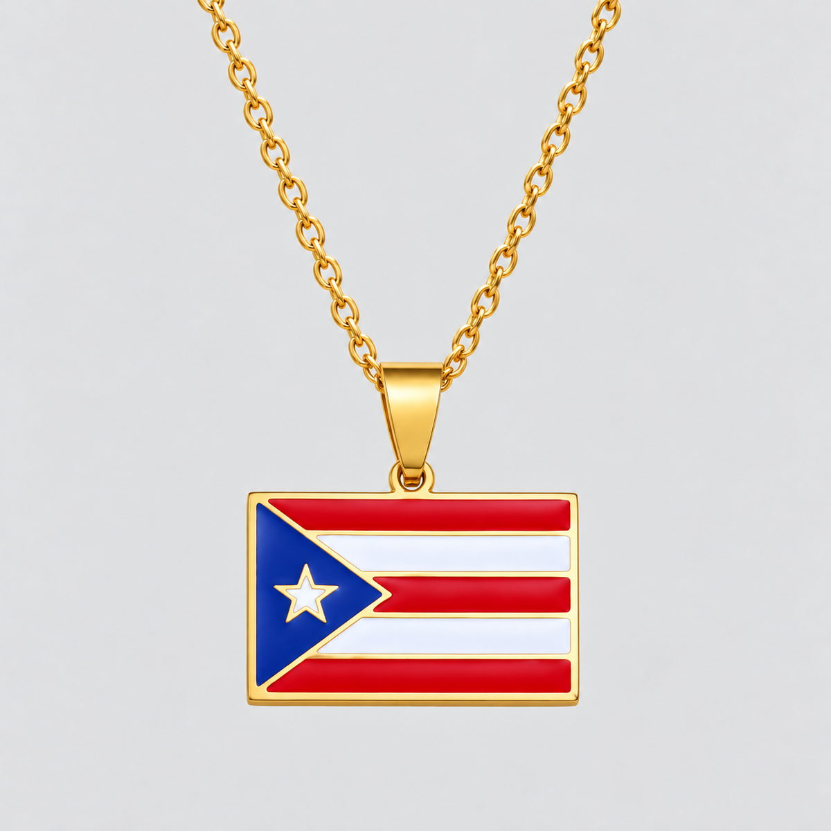 Gold Puerto Rico flag pendant necklace by GRISÉ NYC featuring red, white and blue enamel detailing, polished gold-tone frame and gold cable chain on a light gray background.