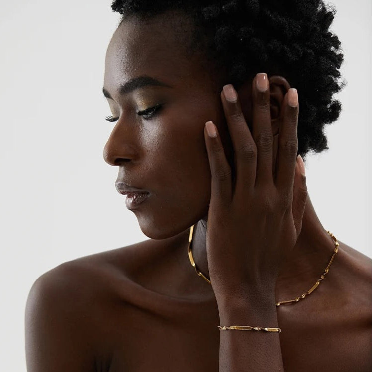 Side profile of model wearing twisted snake chain gold necklace and matching bracelet by GRISÉ NYC.
