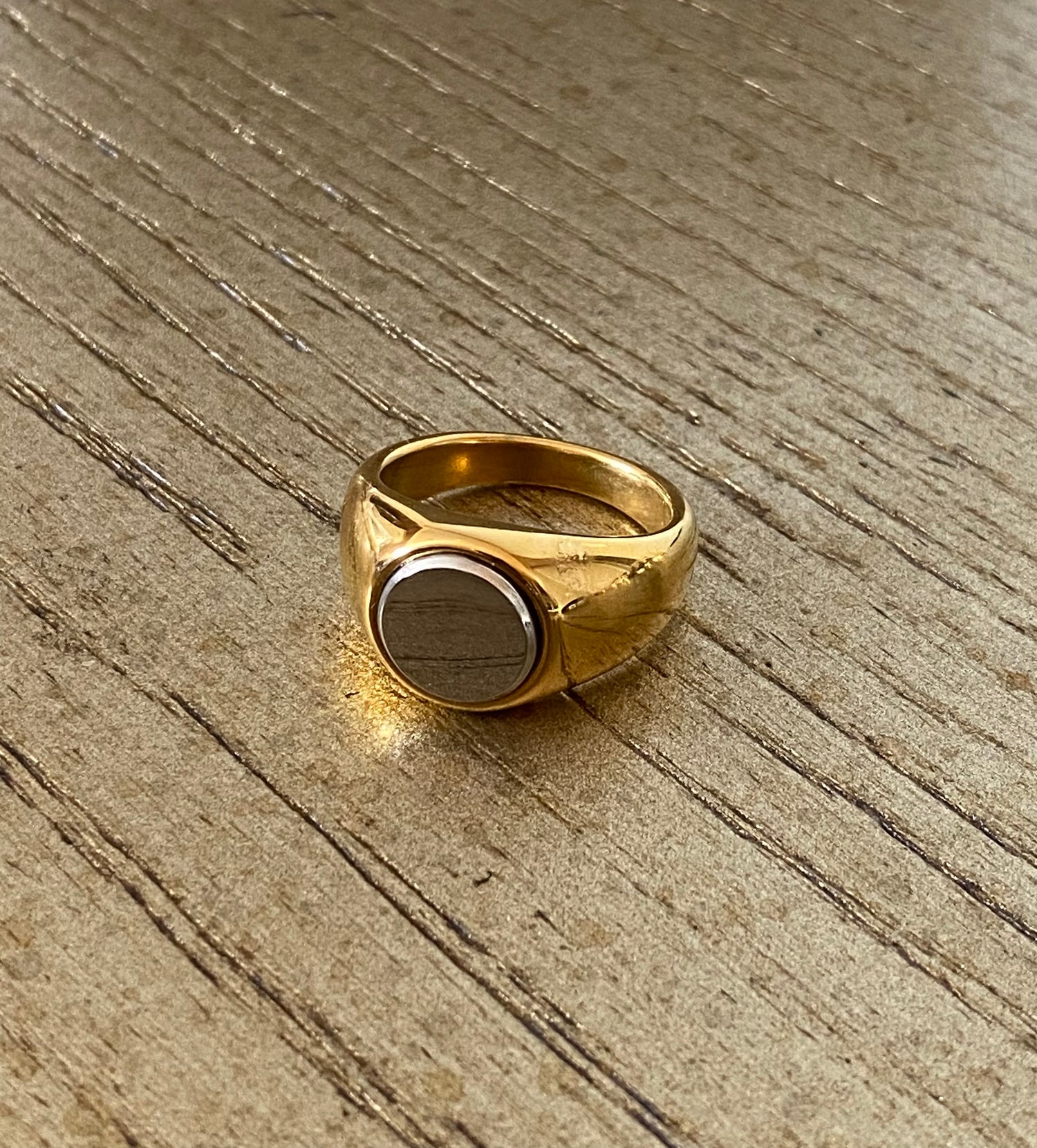 2-Tone Circle Ring by GRISÉ NYC displayed on wood surface highlighting its sculptural gold band and silver center design