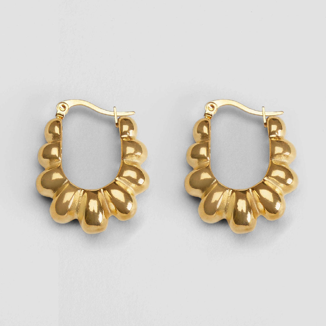 Close-up of GRISÉ NYC Retro Geometric 18k Gold Earrings — sculptural gold-plated stainless steel hoops with bold vintage-inspired shape.
