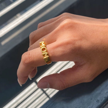Hand wearing a gold ring with &