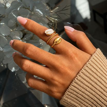 Model wearing the Cowrie Shell 18K Gold Ring featuring an adjustable twisted gold band with dual cowrie shell accents, styled with a cozy knit sweater by GRISÉ NYC.
