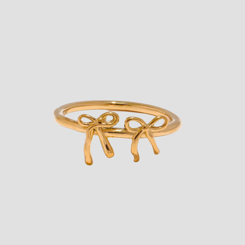 Dainty Double Croquette Bow Ring in 18k gold plated stainless steel featuring two delicate bow designs on a polished gold band by GRISÉ NYC.