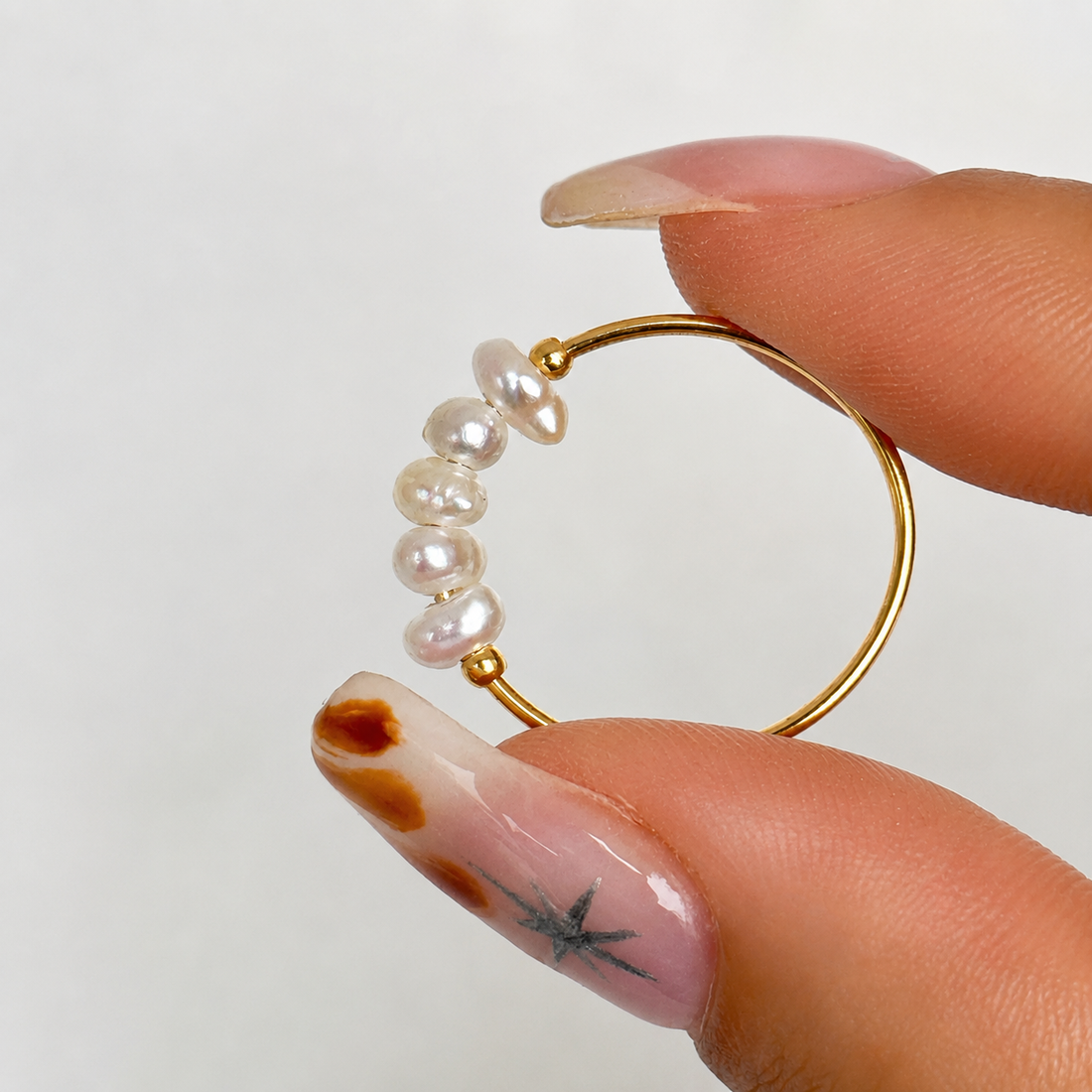 Dainty Freshwater Pearl Ring in 18k gold plated stainless steel with genuine freshwater pearls, held in hand to showcase the delicate minimalist design by GRISÉ NYC.
