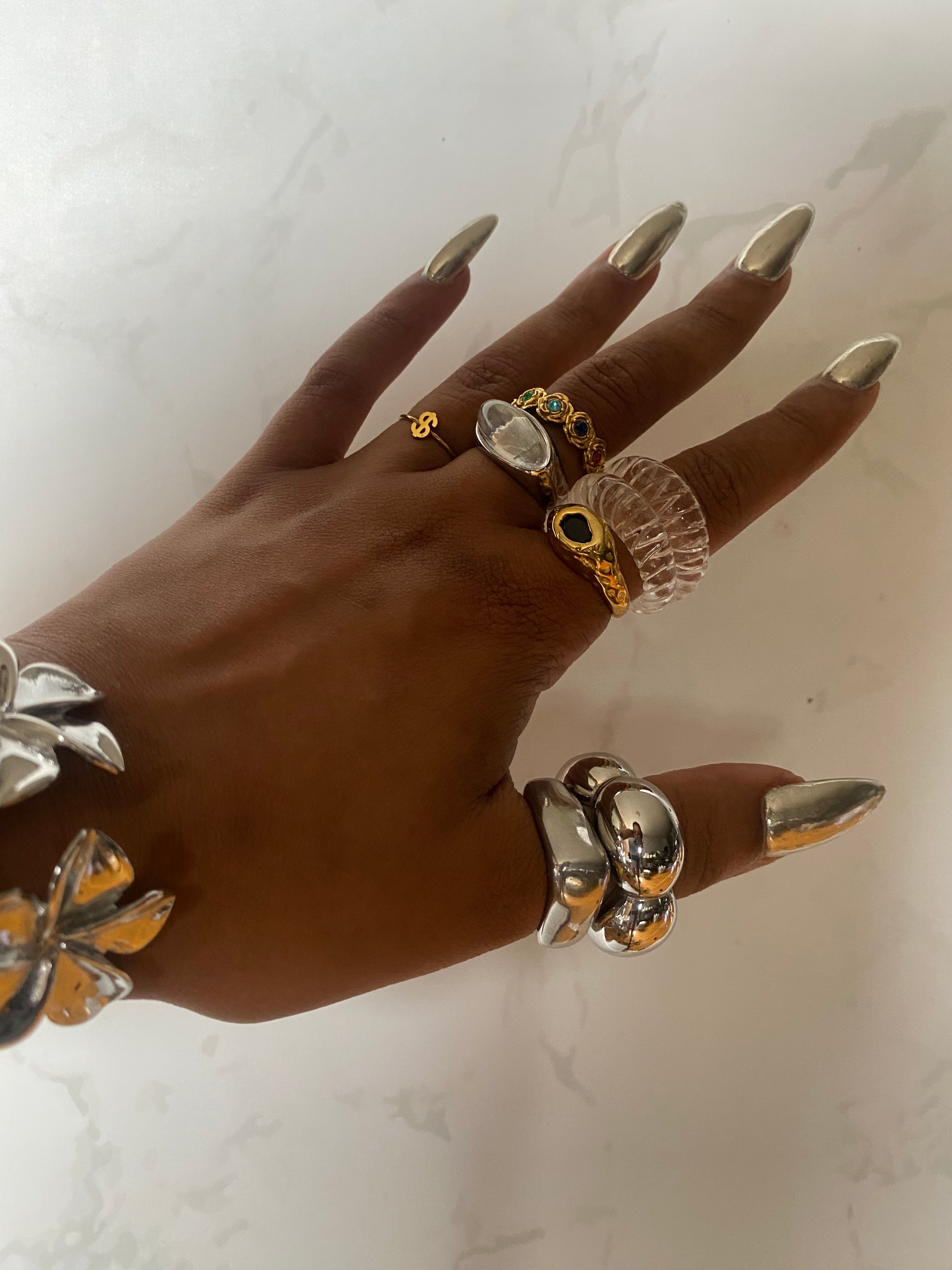 Model styling the Dollar Sign Ring in 18k gold plated stainless steel stacked with other GRISÉ NYC rings and jewelry.