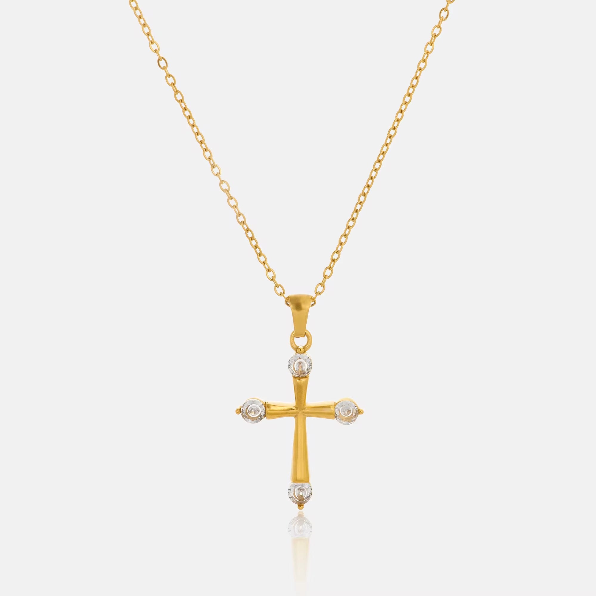 Close-up detail of the Eterna 18K gold cross pendant necklace featuring polished gold plating and brilliant cubic zirconia by GRISÉ NYC.