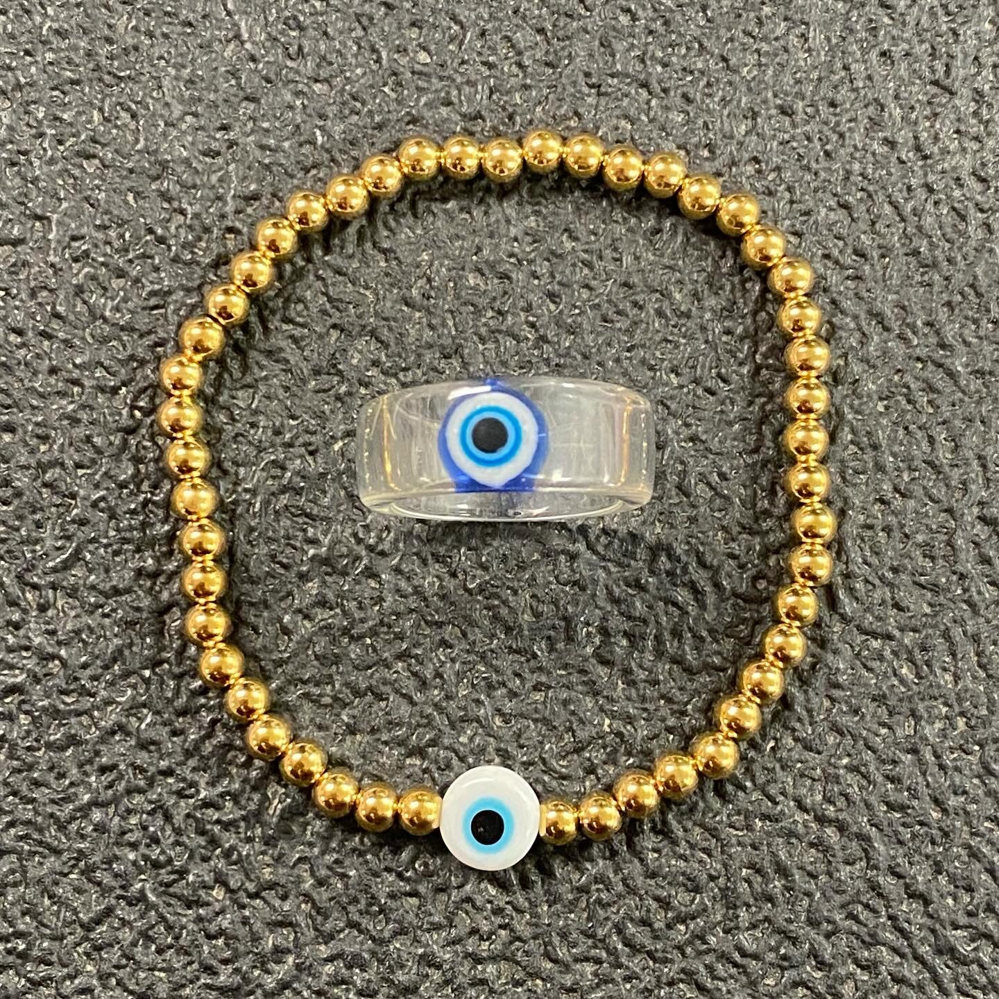 GRISÉ NYC Evil Eye Bead Bracelet featuring polished gold beads and a blue evil eye charm on a neutral background.