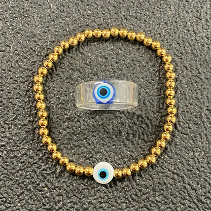 GRISÉ NYC Evil Eye Bead Bracelet featuring polished gold beads and a blue evil eye charm on a neutral background.