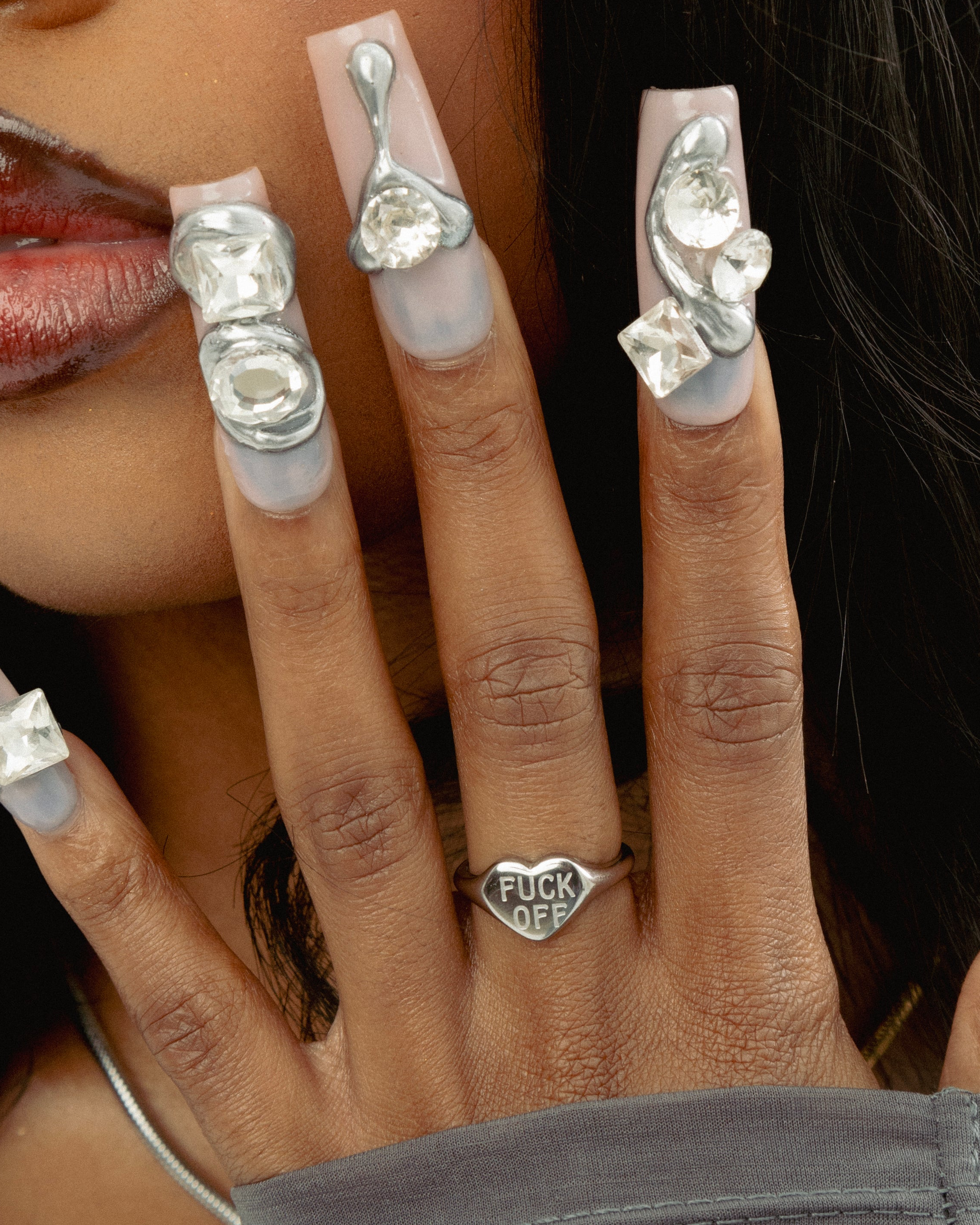Close-up of a hand wearing multiple silver rings with gemstones on a blurred background