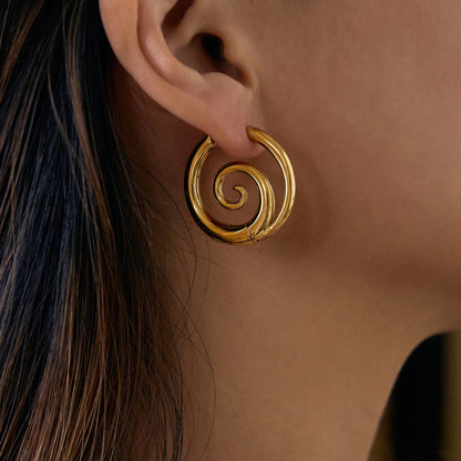 Model wearing GRISÉ NYC 18k gold spiral hoop earrings bold statement gold earrings on ear.