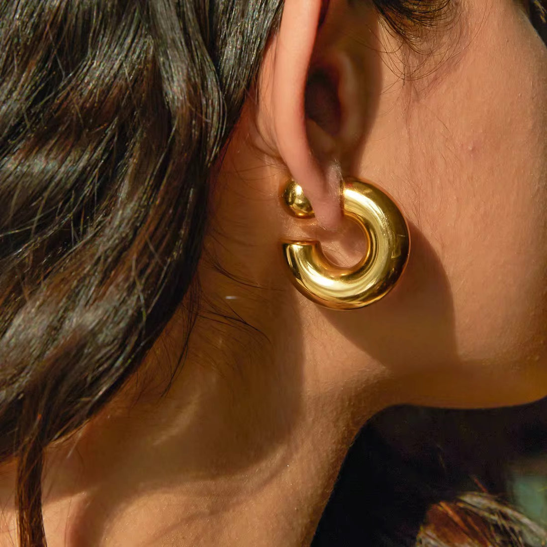 GRISÉ NYC gold 2-in-1 earrings styled on ear with reflective bold design.