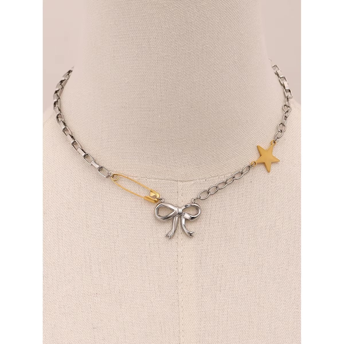 GRISÉ NYC silver bow and gold charm necklace on mannequin head.