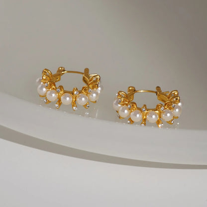 Flat lay of adorned pearl hoop earrings with simulated pearls and gold plated stainless steel by GRISÉ NYC.
