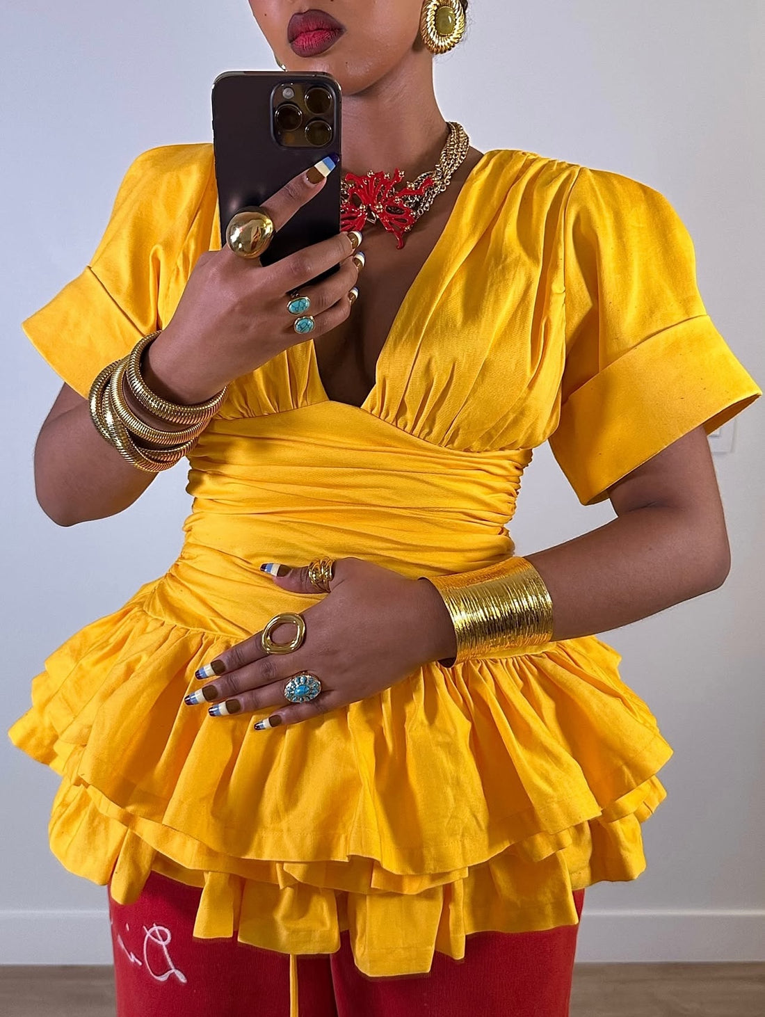 Model wearing armor gold cuff bracelet by GRISÉ NYC, styled with yellow top and red pants.