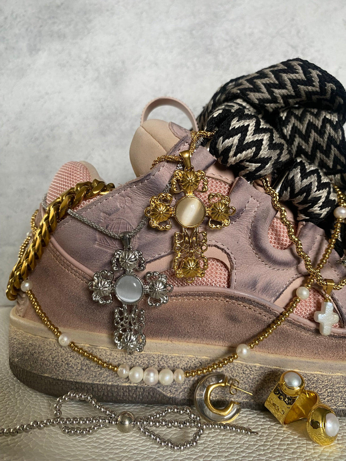 Sneaker art by Georgina Ogirri showcasing the GRISÉ NYC baroque cross pendant necklaces in gold and silver as a layered statement piece.