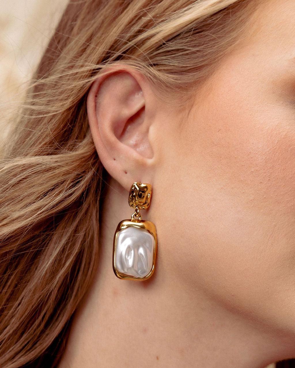 Model wearing GRISÉ NYC baroque pearl drop earrings in gold.
