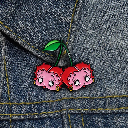 GRISÉ NYC Betty Boop Cherry Enamel Pin styled on denim jacket featuring pink and red cherry character design with green enamel stem detailing