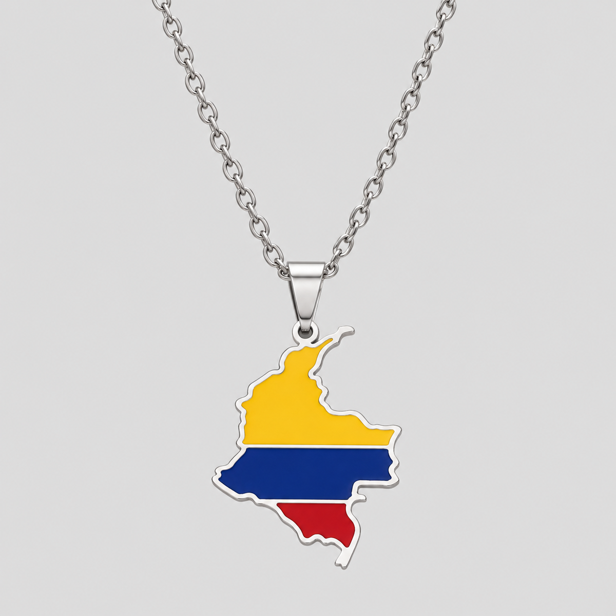 Silver Colombia flag map pendant necklace by GRISÉ NYC featuring yellow, blue, and red enamel detailing, polished silver-tone edges, and a silver cable chain on a light gray background.