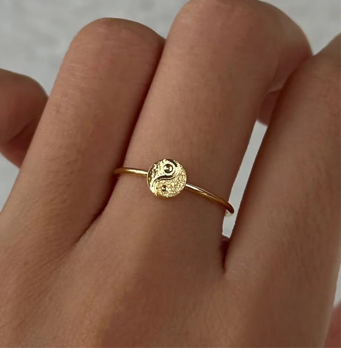 Model wearing the GRISÉ NYC Dainty Ying Yang 18k Gold Ring, a minimalist 18k gold plated stainless steel stacking ring.
