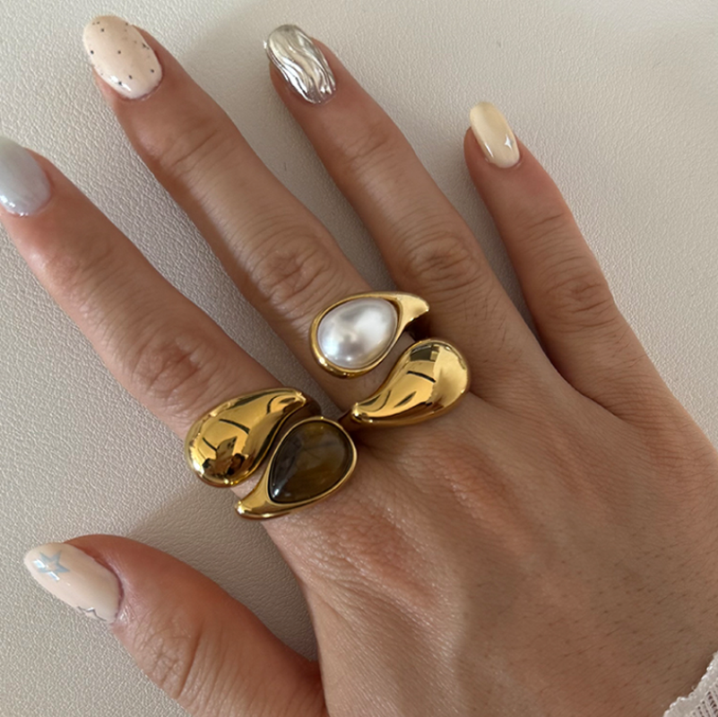 GRISÉ NYC Eclipse Rings stacked on hand featuring freshwater pearl and tiger’s eye stones in 18k gold plated stainless steel.