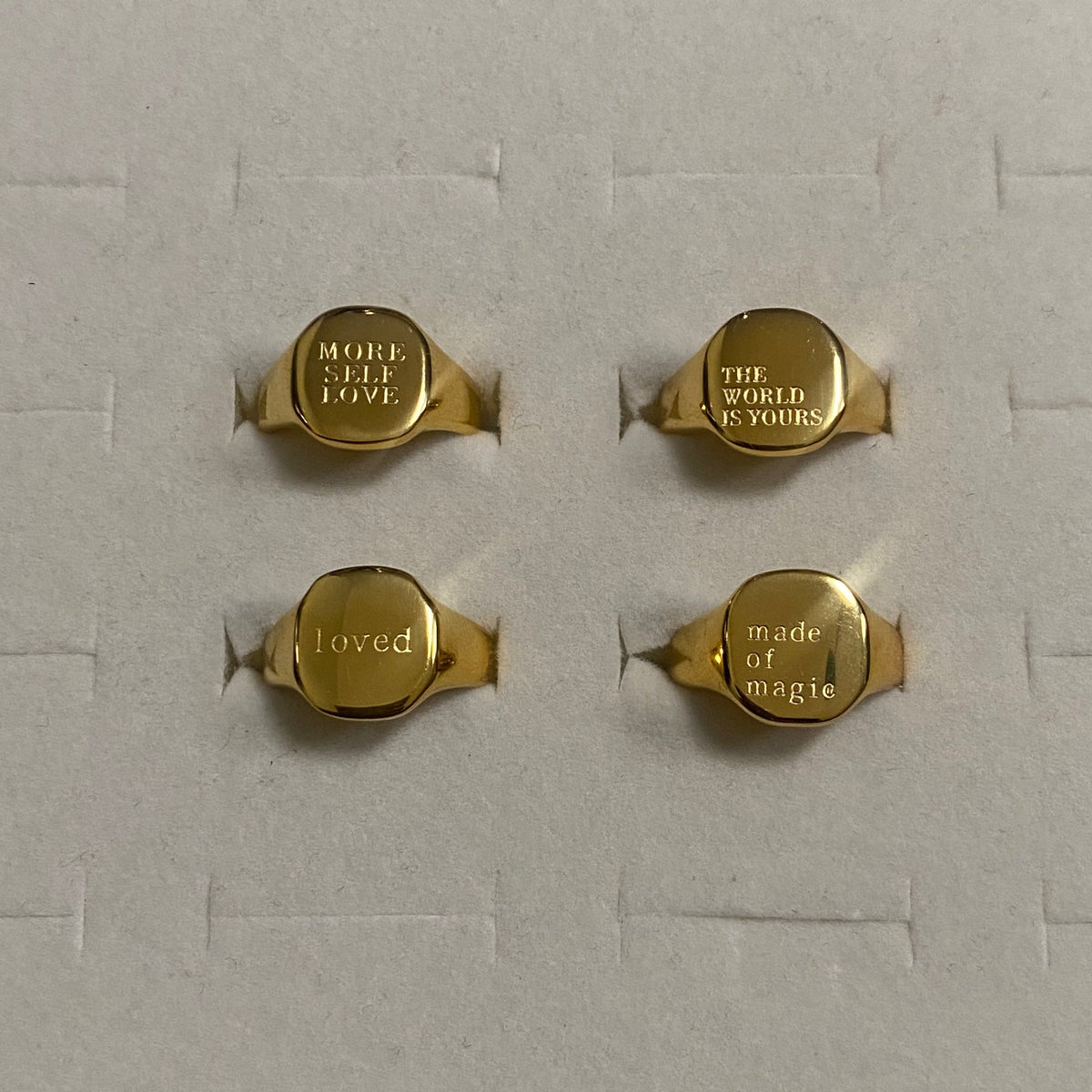 GRISÉ NYC gold engraved signet ring collection featuring MORE SELF LOVE, THE WORLD IS YOURS, loved and made of magic