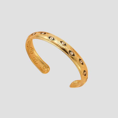 GRISÉ NYC Evil Eye Enamel Cuff Bracelet in 18k gold-plated stainless steel, featuring black and white evil eye enamel details on an open cuff design against a light grey background.