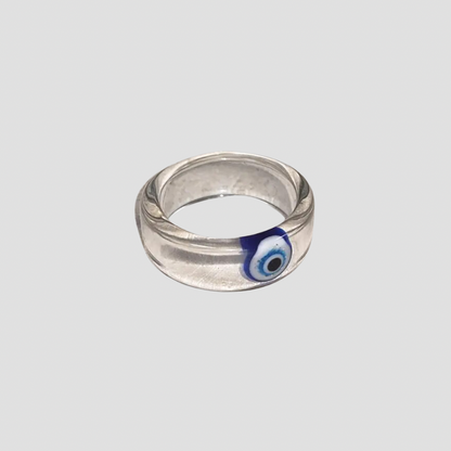 GRISÉ NYC evil eye resin ring with blue talisman detail, laid flat on gray background.