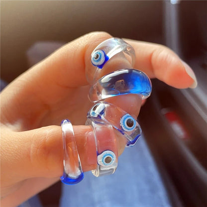 Hand wearing multiple GRISÉ NYC evil eye resin rings stacked together.