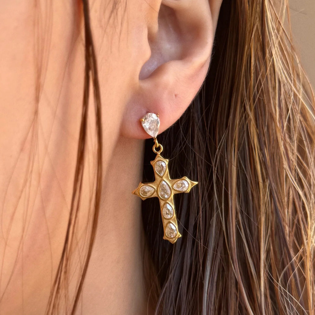 Model wearing GRISÉ NYC gold gemstone cross dangle earrings.