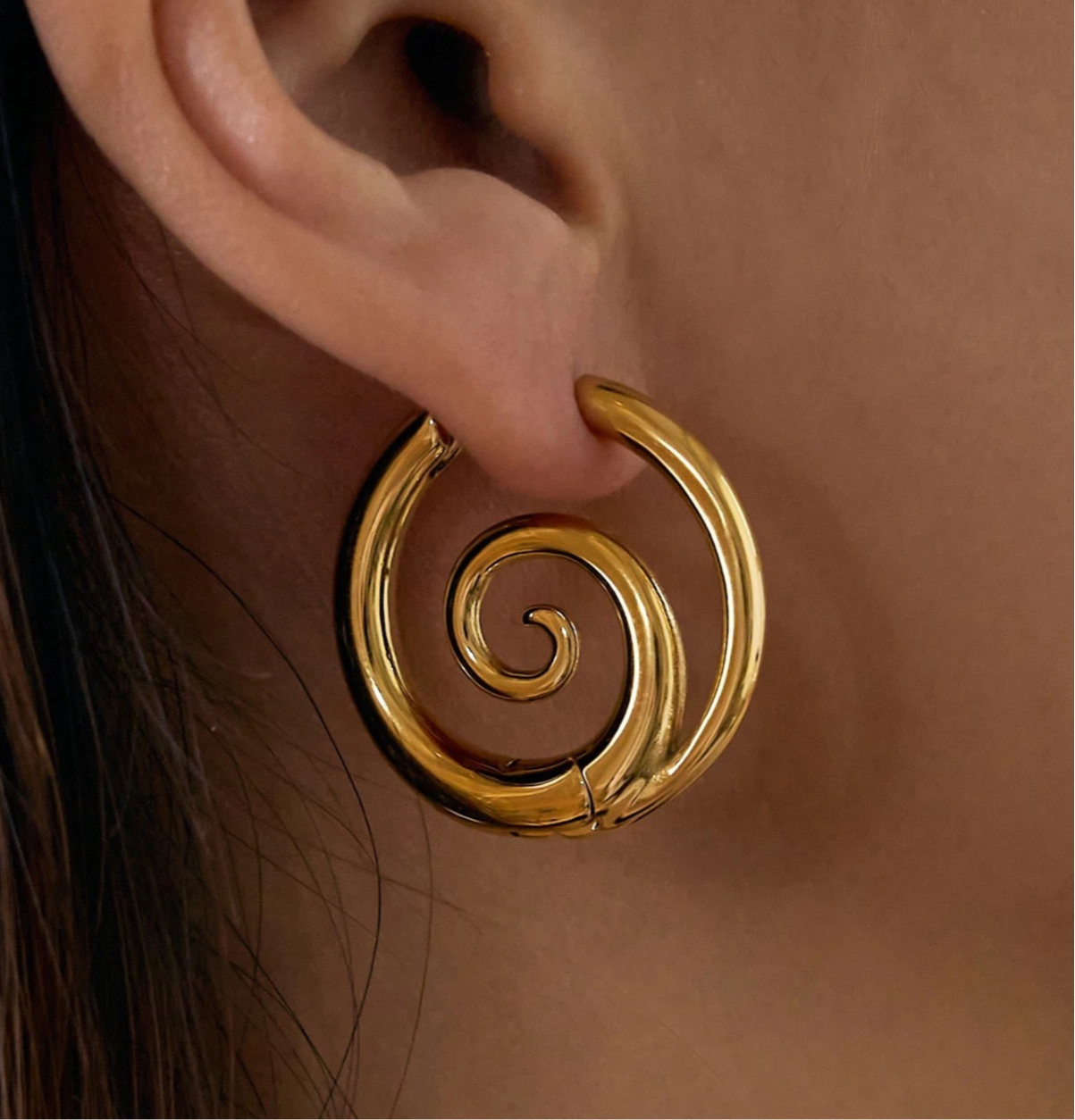 Close detail of GRISÉ NYC 18k gold spiral hoop earrings polished stainless steel gold plated.