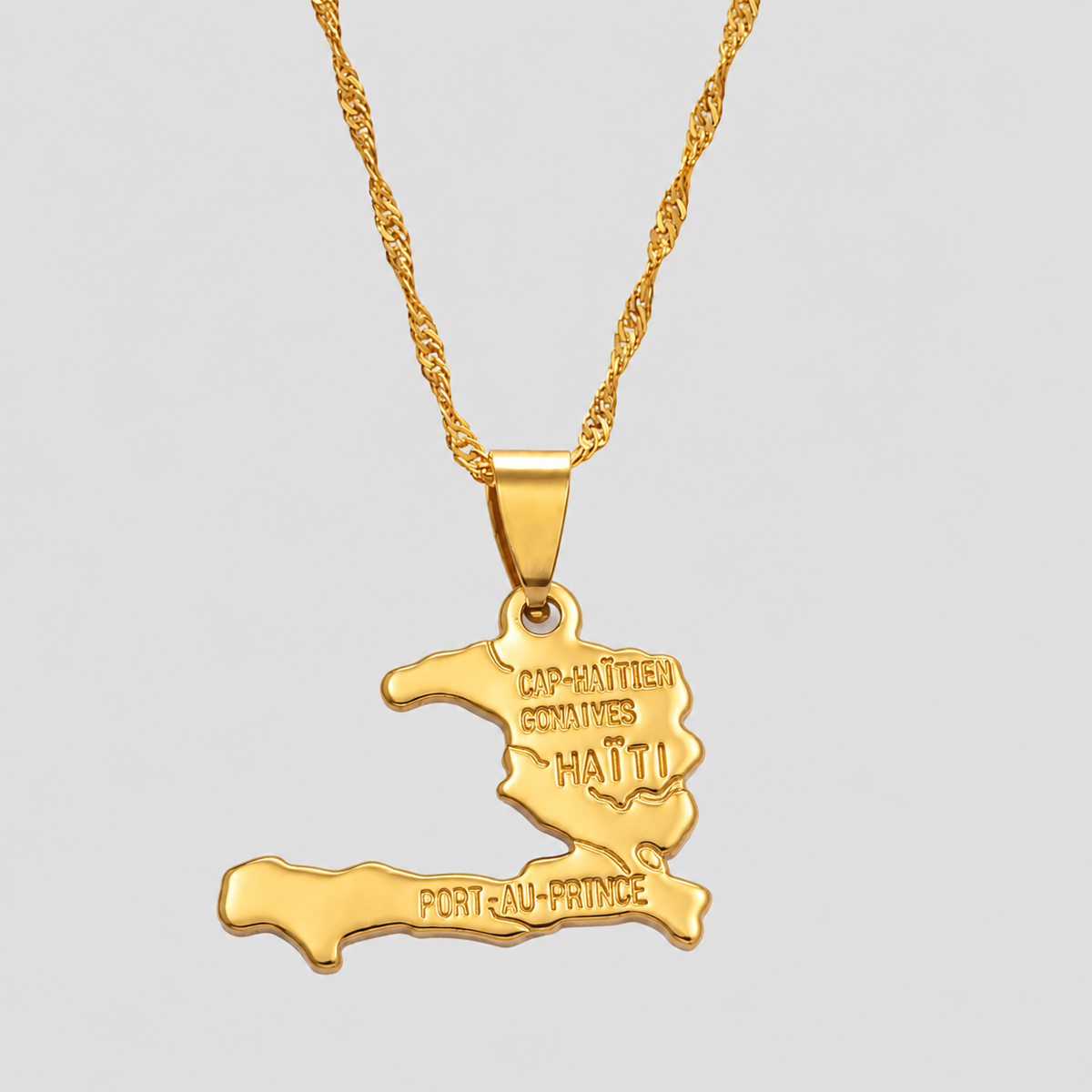 Gold Haiti map pendant necklace by GRISÉ NYC featuring an engraved Haitian map silhouette with Cap-Haïtien, Gonaïves, and Port-au-Prince on a textured gold chain.