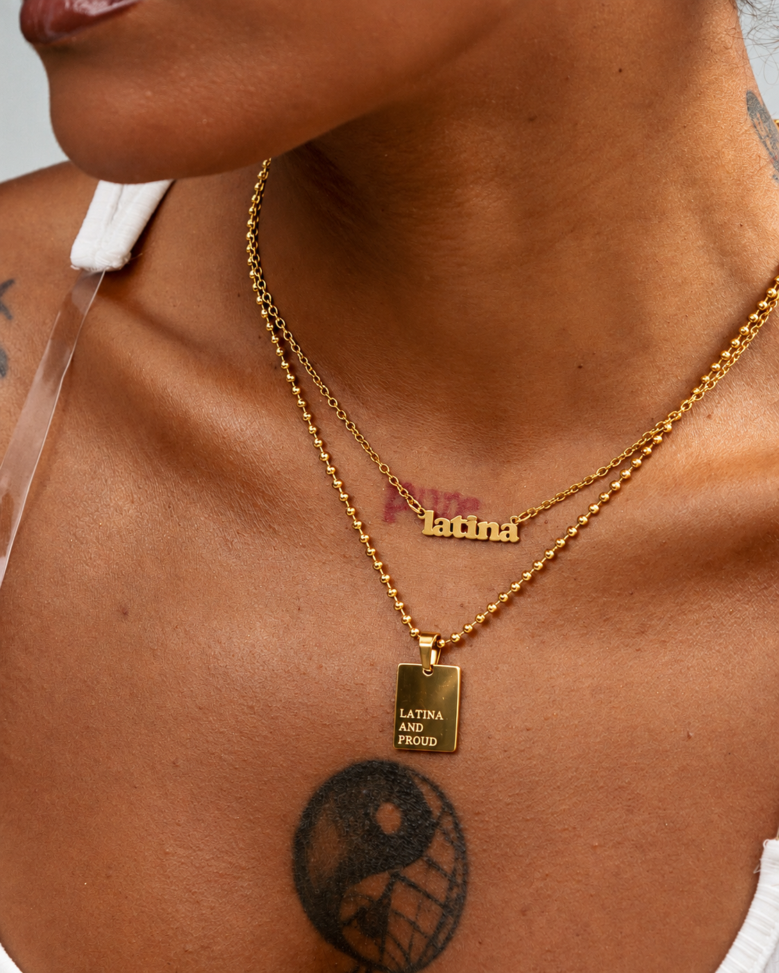 GRISÉ NYC LATINA AND PROUD gold pendant necklace layered with a Latina nameplate necklace.