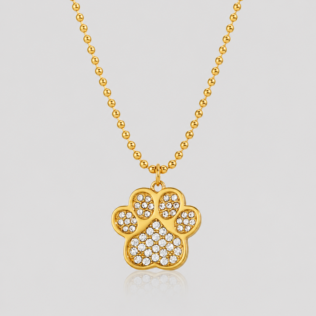 GRISÉ NYC Lucky Paw Crystal Necklace in 18k gold plated stainless steel with sparkling crystal rhinestone paw pendant on light gray background