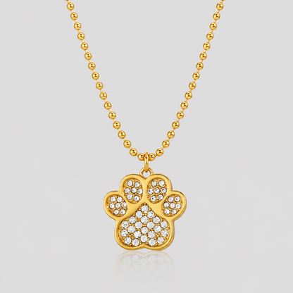 GRISÉ NYC Lucky Paw Crystal Necklace in 18k gold plated stainless steel with sparkling crystal rhinestone paw pendant on light gray background