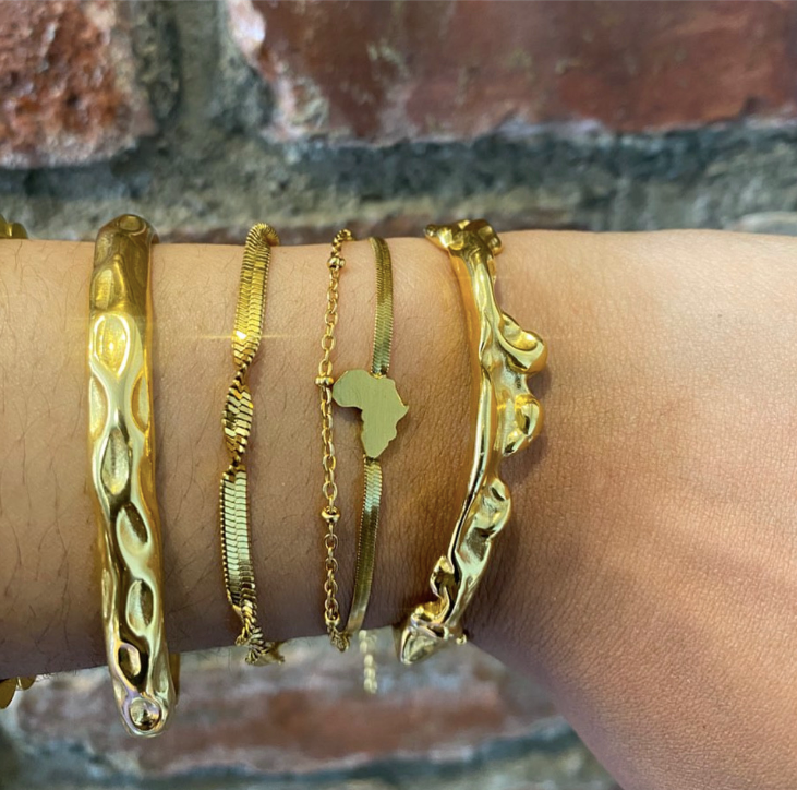 Stacked 18k gold cuff bracelets styled on wrist featuring molten flow cuff by GRISÉ NYC.