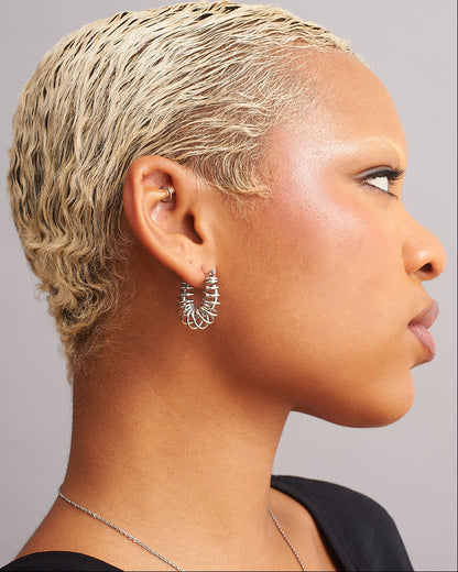 GRISÉ NYC Silver barbed wire hoop earrings worn on ear showing size and fit