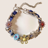 XL Cuban Link Charm Necklace with blue woven chain, colorful flower charms, and mixed metal details on a neutral background.