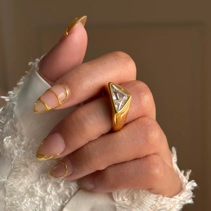 Close up of inverted triangle cubic zirconia gold signet ring worn on finger by GRISÉ NYC.