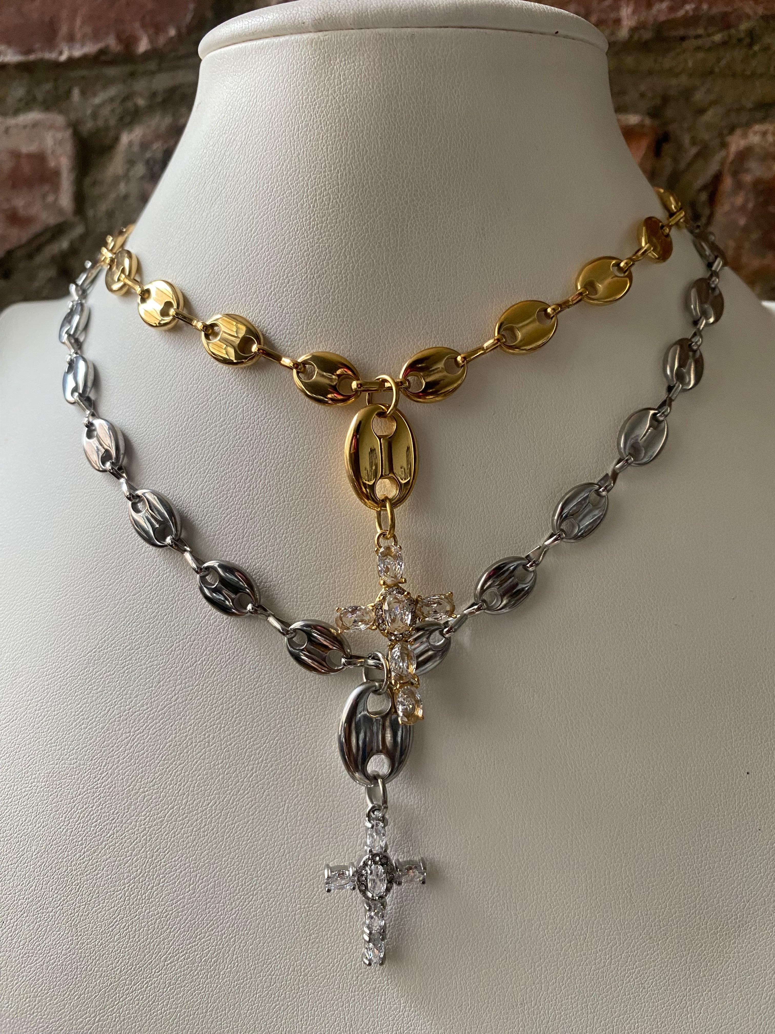 Gold and silver mariner link necklaces layered with gemstone cross pendants close up.