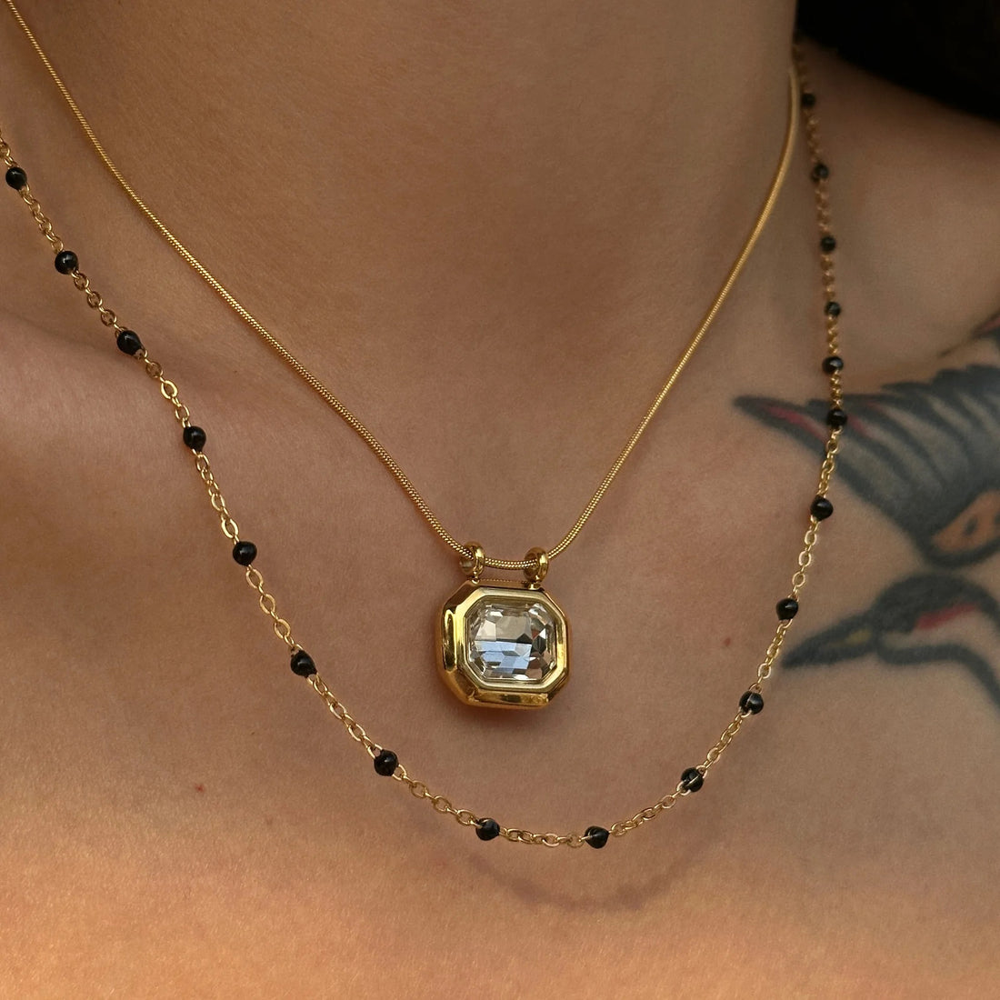 Layered Octo Gemstone Pendant Necklace styled with black beaded necklace and gold chain.
