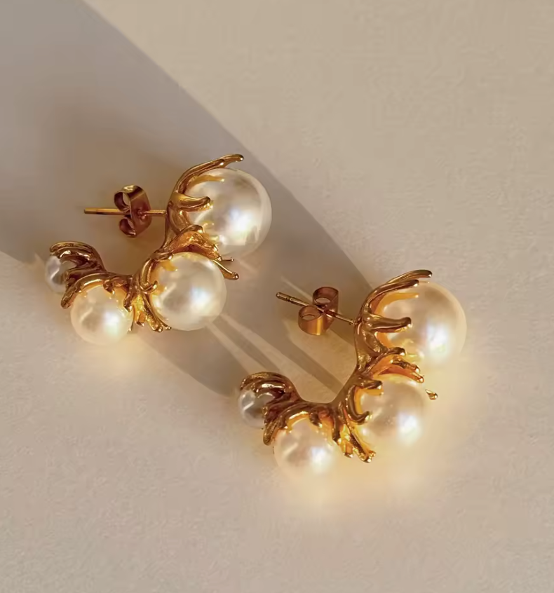 Tres Perlita 18k gold pearl earrings by GRISÉ NYC displayed in warm lighting highlighting textured gold setting and luminous pearls.
