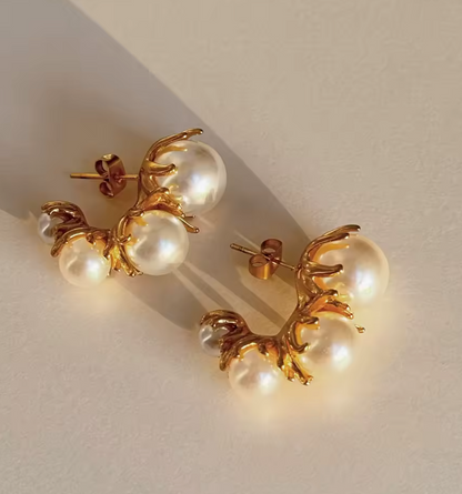 Tres Perlita 18k gold pearl earrings by GRISÉ NYC displayed in warm lighting highlighting textured gold setting and luminous pearls.